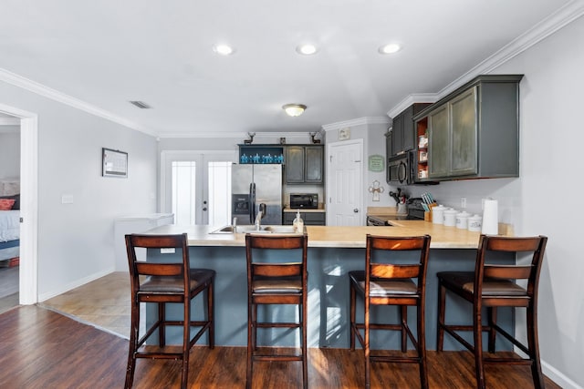 kitchen with black appliances, a breakfast bar, dark hardwood / wood-style flooring, and ornamental molding