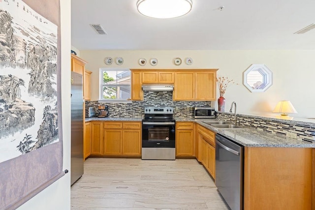 kitchen with backsplash, sink, light hardwood / wood-style flooring, light stone countertops, and stainless steel appliances