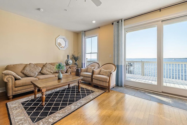 living room featuring ceiling fan, a water view, and hardwood / wood-style flooring