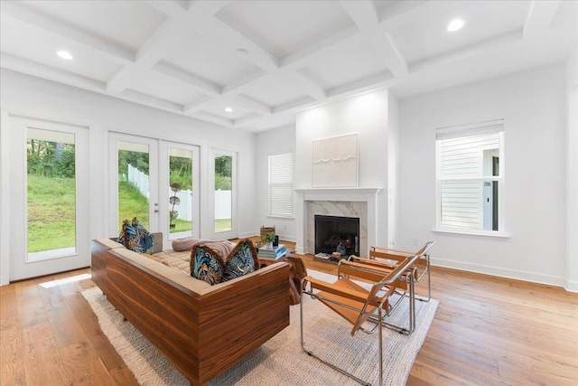 living room featuring a fireplace, light hardwood / wood-style floors, beam ceiling, and coffered ceiling