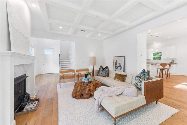 living room with sink, coffered ceiling, beamed ceiling, light hardwood / wood-style flooring, and a high end fireplace