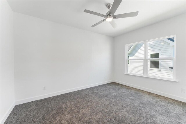 spare room featuring ceiling fan and dark colored carpet