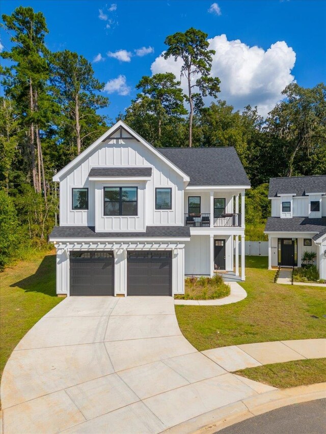 modern farmhouse featuring a front lawn, a garage, and a balcony