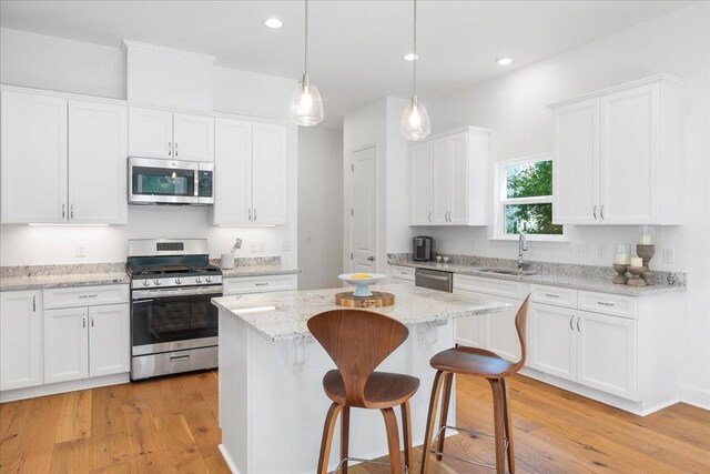 kitchen with light hardwood / wood-style flooring, a kitchen island, white cabinets, and stainless steel appliances