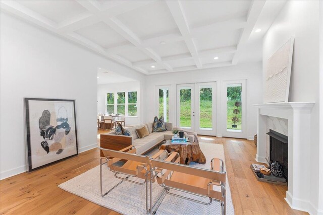 living room featuring a premium fireplace, beam ceiling, light wood-type flooring, and coffered ceiling