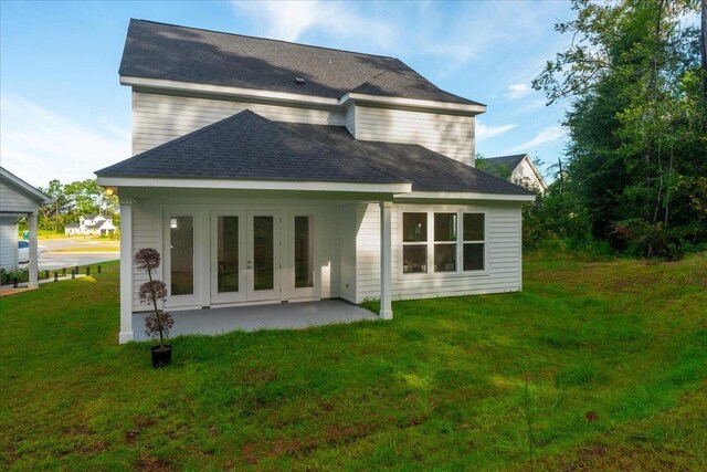 rear view of house featuring a patio area, a lawn, and french doors