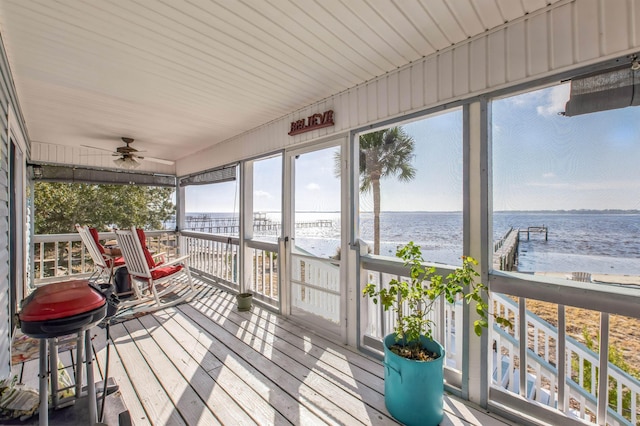 sunroom / solarium with a water view, ceiling fan, and a view of the beach