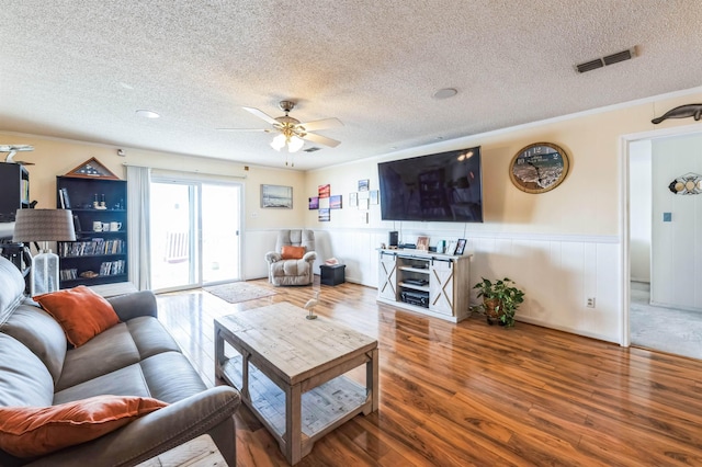 living room featuring ceiling fan, wood-type flooring, and a textured ceiling