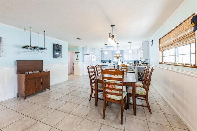 tiled dining area featuring a textured ceiling and ornamental molding