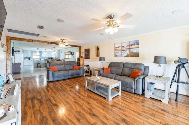 living room with ceiling fan, wood-type flooring, and a textured ceiling