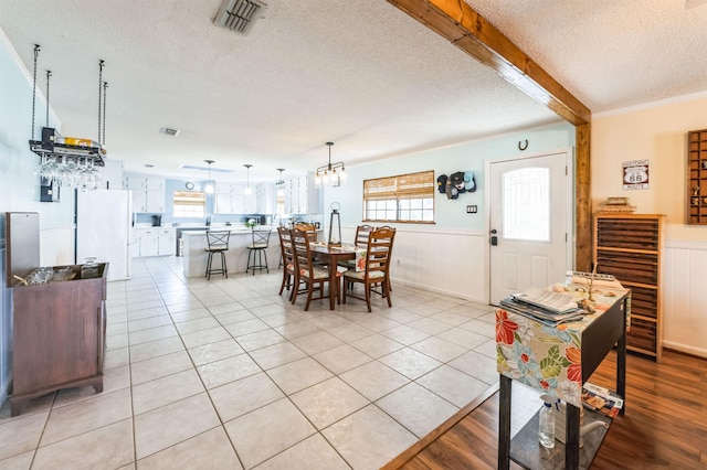 dining room with a healthy amount of sunlight, light tile patterned floors, and a textured ceiling