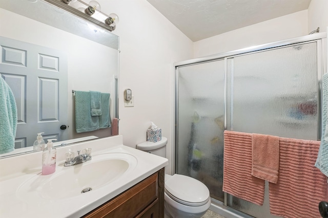 bathroom featuring vanity, toilet, and a shower with shower door