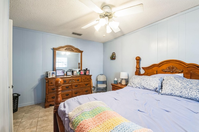 bedroom with ceiling fan, light tile patterned floors, and a textured ceiling