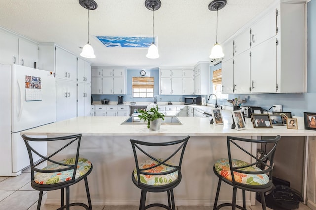 kitchen with white cabinetry, kitchen peninsula, a breakfast bar, white fridge, and black electric cooktop