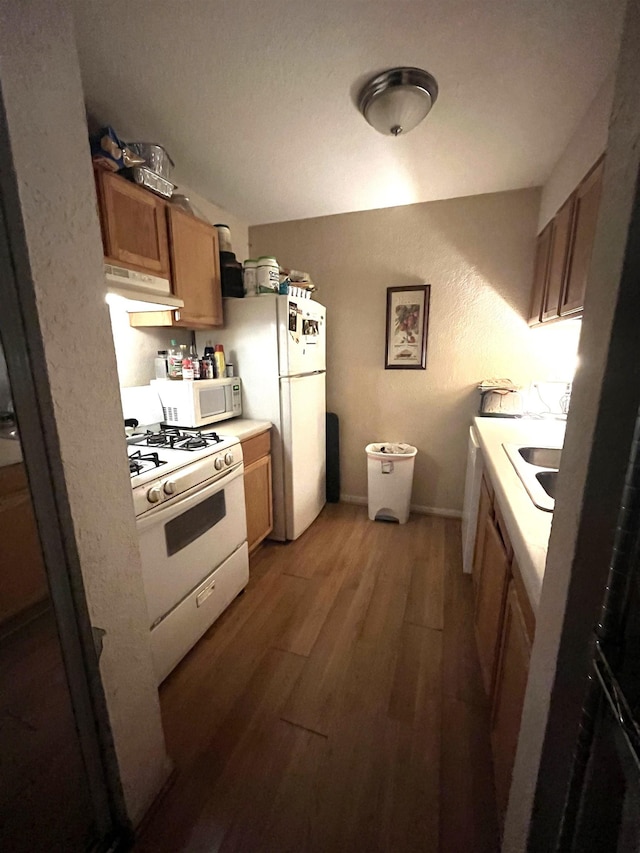 kitchen with white appliances, sink, and hardwood / wood-style floors