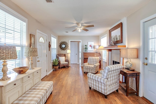 living room featuring a wealth of natural light, ceiling fan, and light hardwood / wood-style flooring