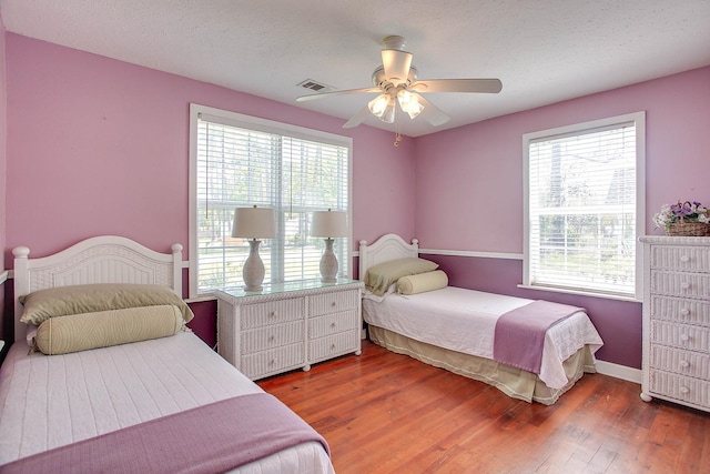 bedroom with a textured ceiling, dark hardwood / wood-style flooring, and ceiling fan