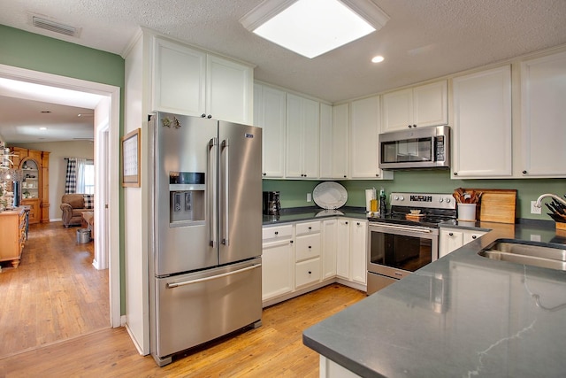 kitchen featuring white cabinetry, light wood-type flooring, appliances with stainless steel finishes, and sink