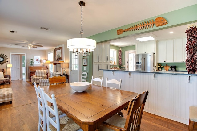 dining room featuring light hardwood / wood-style floors and ceiling fan with notable chandelier