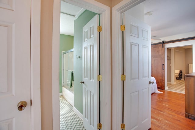 hallway featuring a barn door and light hardwood / wood-style flooring