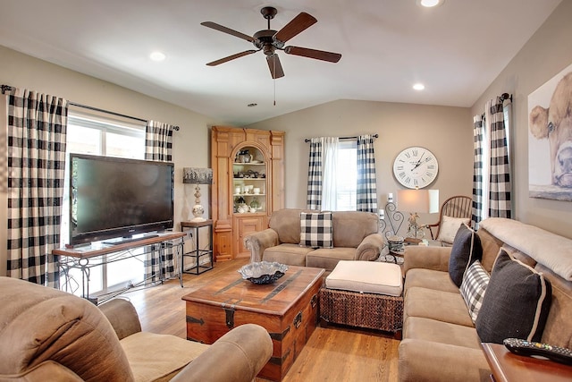 living room featuring a wealth of natural light, ceiling fan, light wood-type flooring, and lofted ceiling