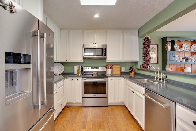 kitchen featuring white cabinets, appliances with stainless steel finishes, sink, and light hardwood / wood-style flooring