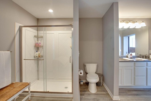 bathroom featuring vanity, hardwood / wood-style flooring, toilet, and a shower with door