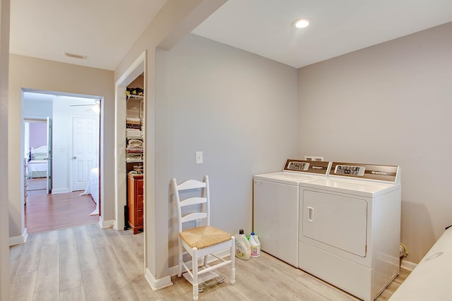 clothes washing area with light hardwood / wood-style flooring and independent washer and dryer