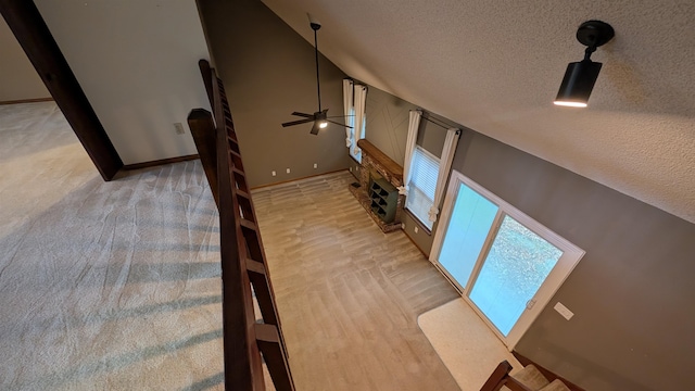 stairway featuring ceiling fan, carpet floors, a textured ceiling, and high vaulted ceiling