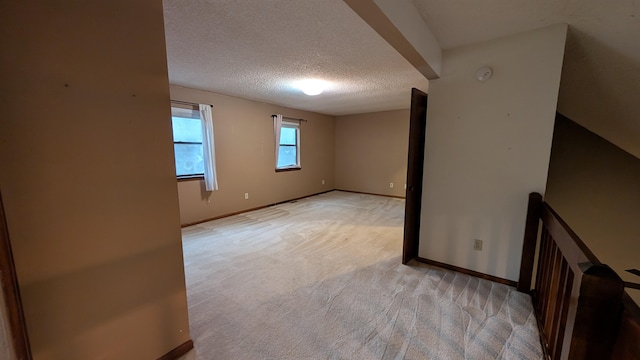 empty room with light colored carpet and a textured ceiling