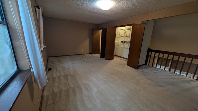 unfurnished room featuring a textured ceiling and light colored carpet