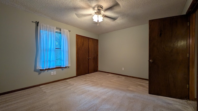 unfurnished bedroom with ceiling fan, a closet, light carpet, and a textured ceiling