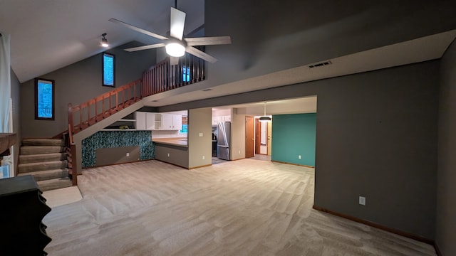 unfurnished living room with light colored carpet, high vaulted ceiling, and ceiling fan