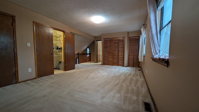 hallway featuring a textured ceiling and light carpet