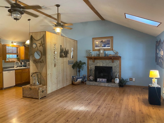 living room with a fireplace, light hardwood / wood-style floors, ceiling fan, and lofted ceiling with skylight