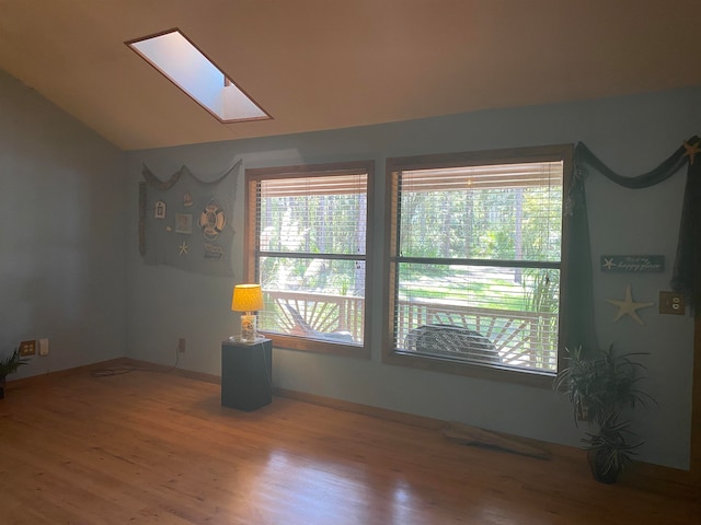 unfurnished room featuring vaulted ceiling with skylight and wood-type flooring