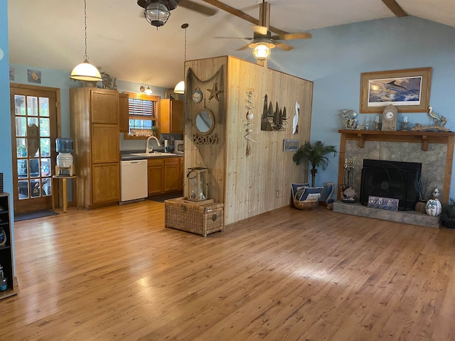 living room with a stone fireplace, sink, ceiling fan, lofted ceiling with beams, and light hardwood / wood-style flooring