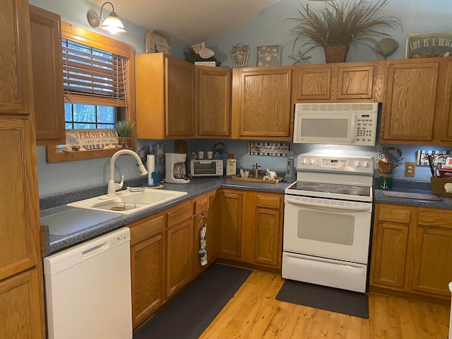 kitchen featuring white appliances, sink, vaulted ceiling, and light hardwood / wood-style flooring