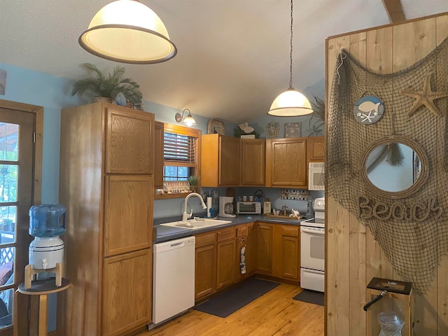 kitchen featuring white appliances, sink, light hardwood / wood-style floors, and hanging light fixtures