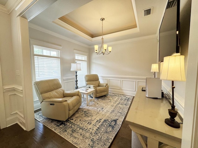 living area with a tray ceiling, dark wood-type flooring, ornamental molding, and a chandelier