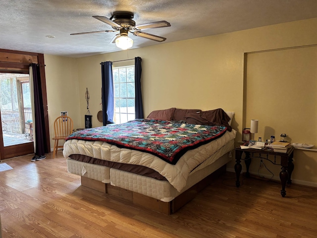 bedroom with ceiling fan, access to outside, a textured ceiling, and light wood-type flooring