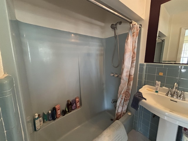 bathroom with sink, tile walls, and shower / bath combo with shower curtain