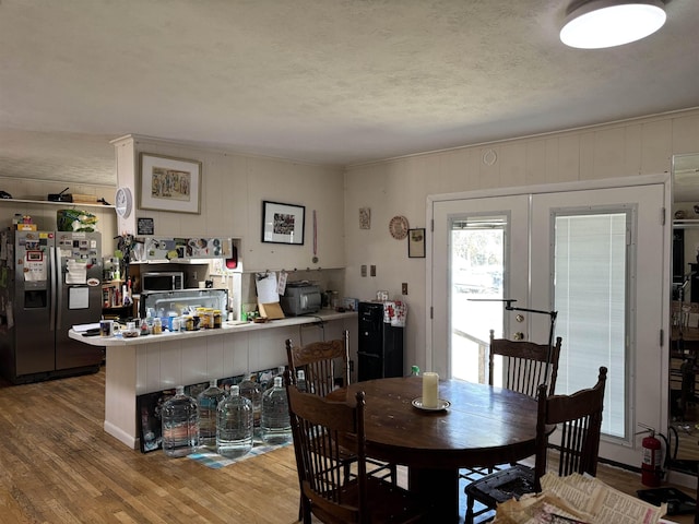 dining room featuring wood-type flooring, a textured ceiling, and french doors