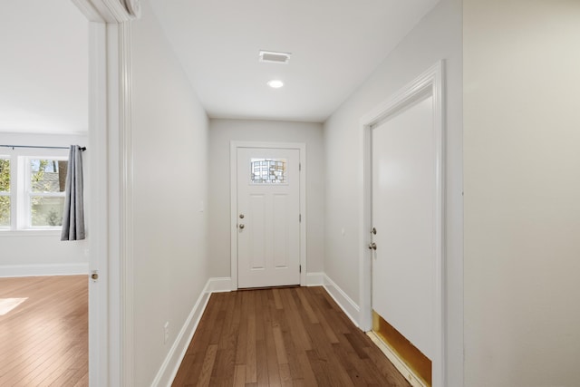 doorway with dark wood finished floors, visible vents, and baseboards