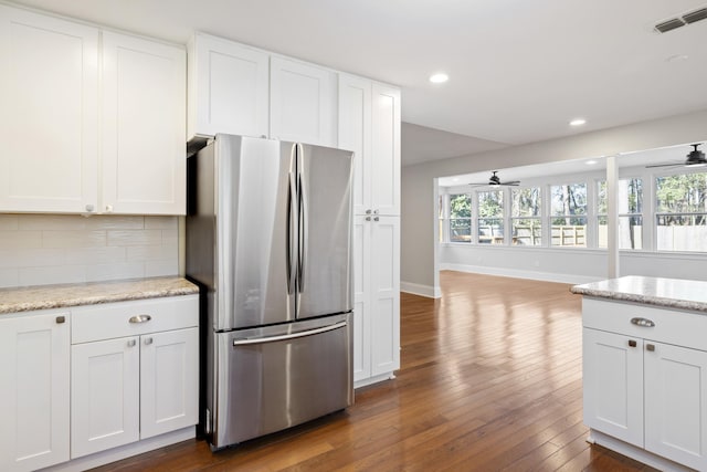 kitchen featuring visible vents, light stone countertops, freestanding refrigerator, and white cabinetry