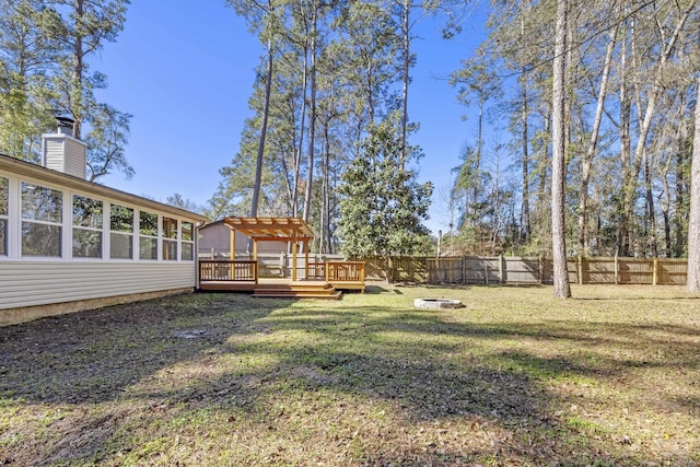 view of yard featuring an outdoor fire pit, a fenced backyard, and a deck