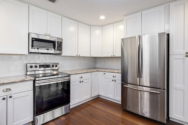 kitchen featuring light stone counters, appliances with stainless steel finishes, dark wood-type flooring, and white cabinetry