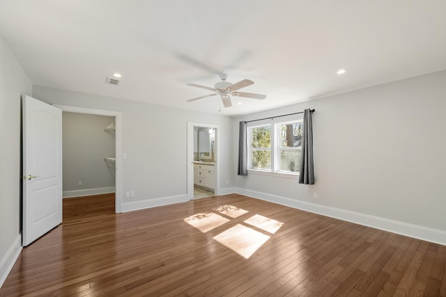 unfurnished bedroom with a closet, visible vents, a spacious closet, dark wood-type flooring, and baseboards