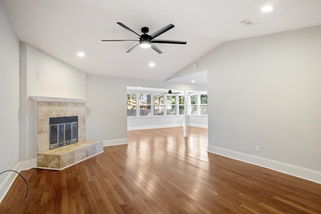 unfurnished living room featuring ceiling fan, wood finished floors, a high end fireplace, baseboards, and vaulted ceiling