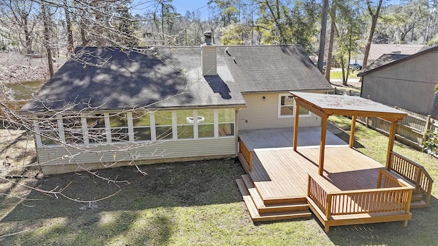 back of house with a sunroom, a chimney, roof with shingles, a deck, and a yard